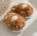 Pair of brown fuzzy slippers with white bottoms on a light surface.